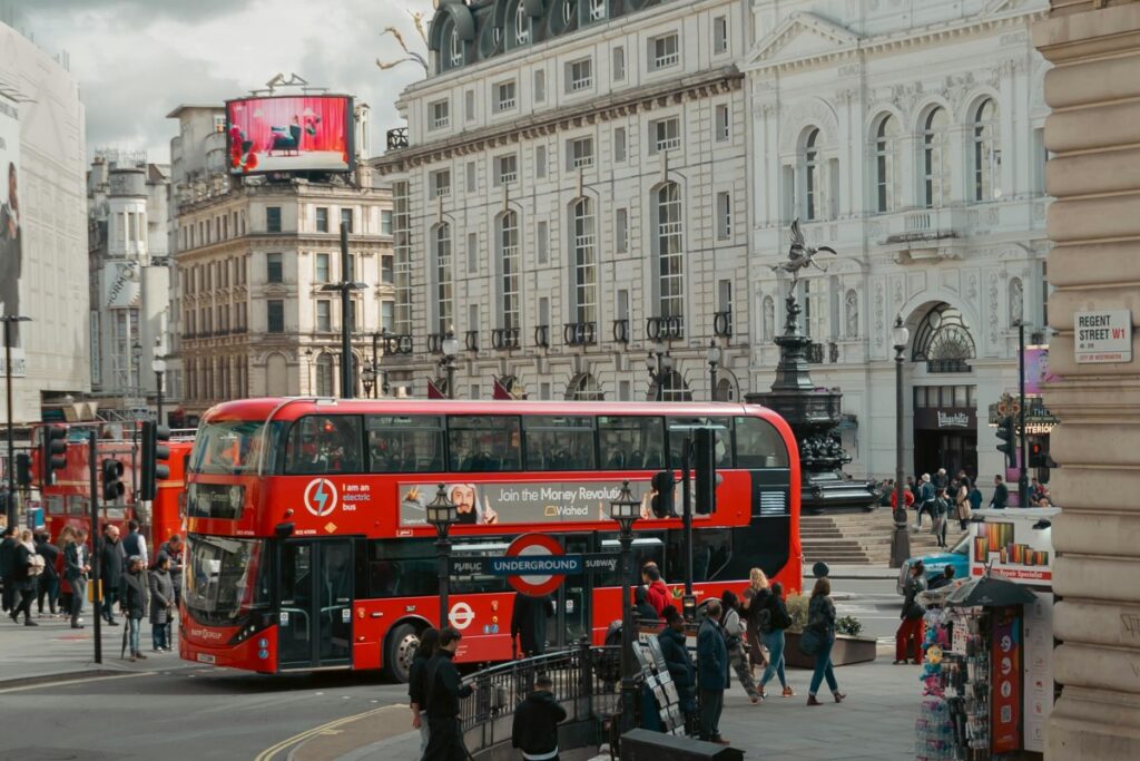 A bustling street scene in the UK features a classic red double - decker bus amidst pedestrians and historic buildings. There are advertisements on the bus and billboards overhead. About BaoLiba – Transforming Influencer Marketing in the UK: This vibrant urban setting showcases the dynamic environment where BaoLiba can revolutionize influencer marketing, leveraging the country's iconic elements.